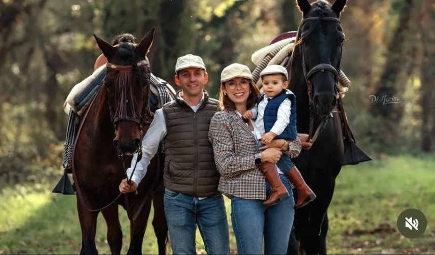 Familia posando junto a dos caballos en un bosque otoñal